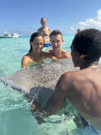 A couple interacts with a stingray in shallow turquoise waters, creating a memorable wildlife experience in a tropical paradise.