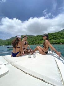 Three friends relax on the deck of a yacht, enjoying drinks and the beautiful scenery — a perfect moment for a summer getaway.