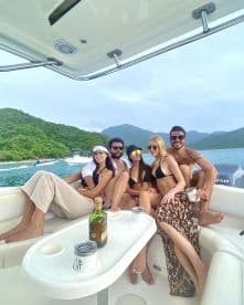 A lively group enjoys a fun day on the boat, sharing drinks and laughter against a scenic backdrop of lush hills — perfect for summer celebrations and memorable outings.