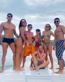 A vibrant group of friends poses on the deck of a boat, enjoying a fun day on the water — perfect for summer celebrations and memorable outings.