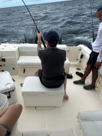 Two individuals enjoy a fishing trip aboard a boat, showcasing the excitement of on-water activities and camaraderie.