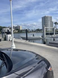 A sleek speedboat is docked at the marina, with a scenic backdrop of buildings and palm trees, perfect for a day on the water.