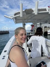 A woman smiles while seated at the helm of a boat, showcasing the comfortable interior space designed for navigation and relaxation.