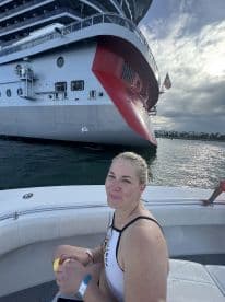 A woman enjoys a moment of relaxation on a boat with a large cruise ship in the background, capturing the essence of a fun day on the water.