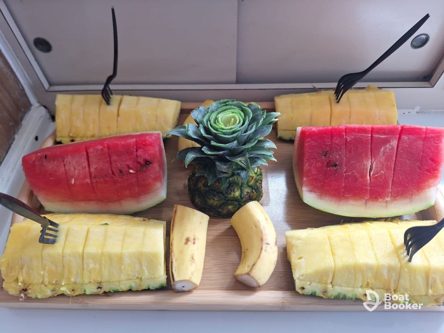 A vibrant display of fresh fruit including watermelon, pineapple, and bananas, perfect for enjoying on a boat trip or as a refreshing snack.