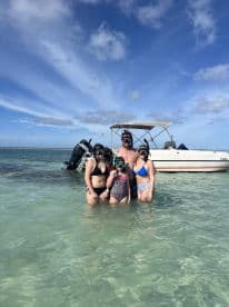 A family enjoys a fun snorkeling adventure in clear waters, posing together with their boat in the background — perfect for memorable aquatic experiences.