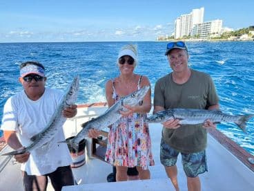 A group of anglers proudly displays their catch of the day while fishing in vibrant blue waters — a perfect moment of celebration on a fishing trip.