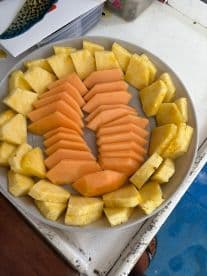 A beautifully arranged platter of fresh pineapple and cantaloupe, perfect for a refreshing snack on board during a boating adventure.