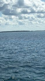 A scenic view of the ocean with clouds overhead, capturing the tranquil beauty of the water and distant land.