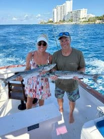 A happy couple proudly displays their catch while fishing on a boat, showcasing a successful day on the water.