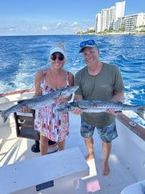 A couple proudly displays their impressive catch while fishing on a boat, showcasing the thrill of a successful day on the water.