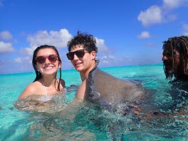A couple enjoys a thrilling encounter swimming with a stingray in crystal-clear waters, capturing a memorable wildlife experience in the tropics.