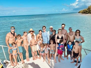 A joyful family group poses together on the deck of a boat, enjoying a sunny day on the water — perfect for memorable family outings and celebrations.
