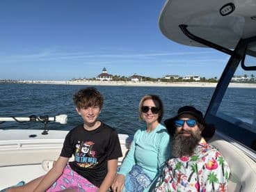 A family enjoys a sunny day on the boat, with a scenic beach backdrop — perfect for creating lasting memories on the water.