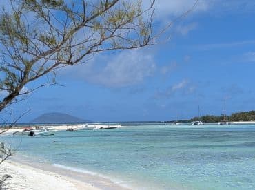 A picturesque view of a beach with multiple boats anchored near the shore, showcasing the stunning coastline and inviting waters — perfect for a day of relaxation and exploration.