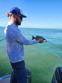 A man proudly displays his catch while fishing on a boat, showcasing the thrill of ocean fishing adventures.