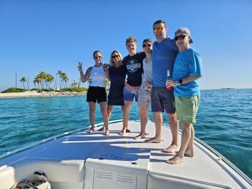 A lively group of friends enjoys a sunny day on the boat, celebrating together against a beautiful island backdrop — perfect for memorable outings and adventures on the water.