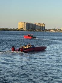 A sleek speedboat navigates the water, showcasing its vibrant design against a backdrop of waterfront buildings — perfect for thrilling water adventures.