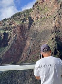 A guest captures the stunning cliffside scenery during a boat tour, showcasing the breathtaking natural beauty of the coastline.