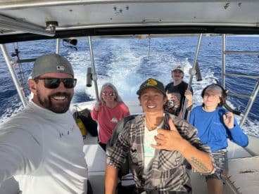 A cheerful group of friends enjoys a day on the water, capturing the excitement of their fishing adventure aboard a boat.