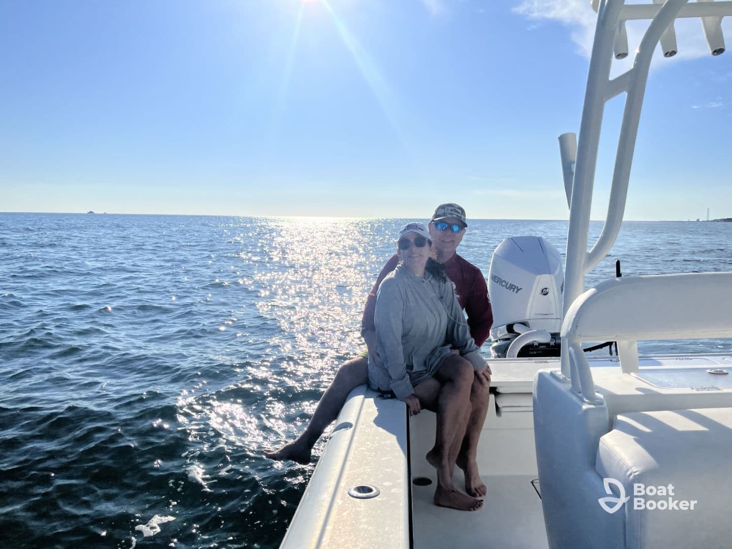 A couple enjoys a sunny day on the water, capturing a romantic moment aboard their boat with sparkling ocean waves in the background.