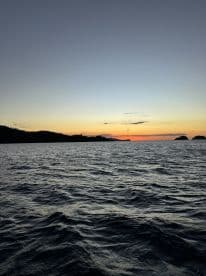A serene sunset view over calm waters, showcasing the beautiful coastline — perfect for tranquil evening boat rides.