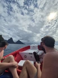 A group enjoys a scenic boat ride with stunning views of the Pitons in the background, perfect for adventure seekers exploring the beauty of the Caribbean.