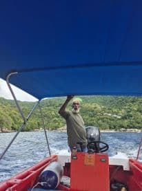 A boat captain navigates the waters, showcasing the beautiful lush landscape in the background — a perfect representation of local boating experiences.