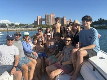 A joyful group of friends and family enjoy a day on the water, with the iconic Atlantis resort in the background — perfect for memorable boat outings and celebrations.