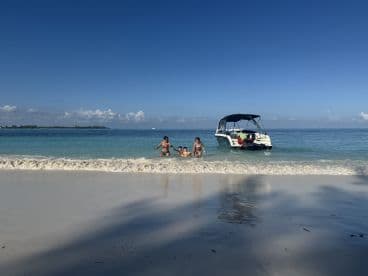 A family enjoys a fun day at the beach, playing in the shallow water near their boat — a perfect setting for summer adventures and family bonding.