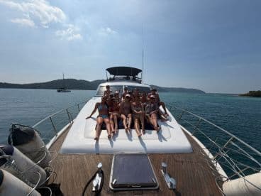A lively group enjoys sunbathing on the deck of a yacht, capturing the essence of a fun day on the water with friends.