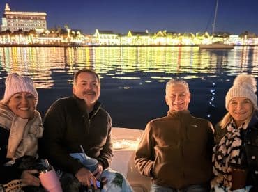A cheerful group enjoys a night out on the water, surrounded by festive lights reflecting on the water — perfect for evening cruises and celebrations.