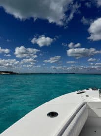 A stunning view of a boat's edge gliding through crystal-clear turquoise waters under a vibrant sky, perfect for showcasing the beauty of a day on the water.