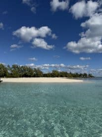 A stunning view of a secluded beach with crystal-clear waters and lush greenery, perfect for island hopping adventures or relaxing getaways.