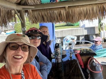 A cheerful group of friends enjoys a day on the water, capturing memories with smiles and fun hats while preparing for their boating adventure.