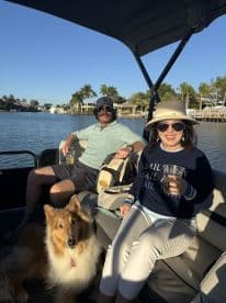 A couple enjoys a relaxing day on the water with their dog, sipping drinks on a boat — a perfect setting for a leisurely outing.