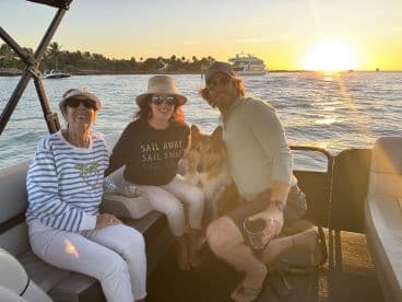 A joyful group enjoys a sunset cruise on a boat, accompanied by their dog, capturing a perfect moment of family togetherness and celebration on the water.