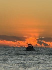 A boat navigates through shimmering waters at sunset, creating a picturesque scene perfect for evening cruises and relaxation on the water.