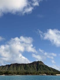 A stunning view of a lush mountain landscape under a bright blue sky, showcasing the natural beauty of the coastline — perfect for nature lovers and scenic boat tours.