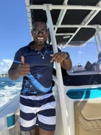 A cheerful individual poses on a boat, giving a thumbs up against a backdrop of vibrant blue waters — perfect for showcasing the fun and excitement of a boating adventure.