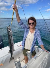 A joyful angler proudly displays her catch while fishing on a boat, showcasing the excitement of a successful day on the water.