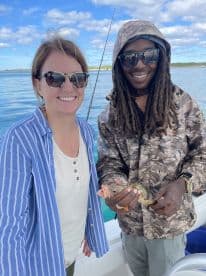 A joyful moment captured with two friends proudly displaying their catch while fishing in the beautiful ocean — a perfect day on the water.