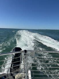A view from the back of a boat cruising through clear waters, showcasing the engine and wake trail behind — perfect for adventure seekers on the water.