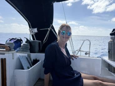 A woman relaxes in the interior of a sailboat, enjoying the serene ocean views — perfect for a day of sailing adventures.