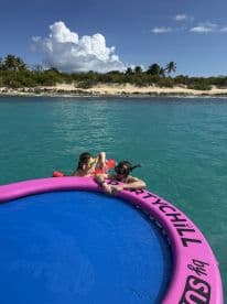 A couple enjoys a fun day snorkeling and relaxing on a floating mat in the clear turquoise waters, surrounded by a beautiful beach backdrop.
