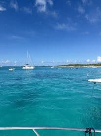 A stunning view of multiple boats anchored in crystal-clear turquoise waters, showcasing the beauty of the coastline and inviting adventure on the water.