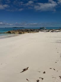 A serene view of a pristine beach with turquoise waters and rocky formations, perfect for island getaways and relaxation.