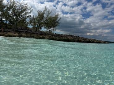 A serene view of clear turquoise waters and rocky coastline, capturing the beauty of a beach destination — perfect for relaxation and exploration.