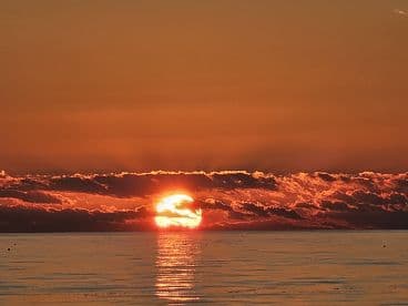 A stunning sunset over calm waters, creating a picturesque scene perfect for evening boat cruises and relaxation on the water.