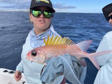 A proud angler holds up a vibrant fish caught during a fishing trip, showcasing the thrill of ocean fishing adventures.